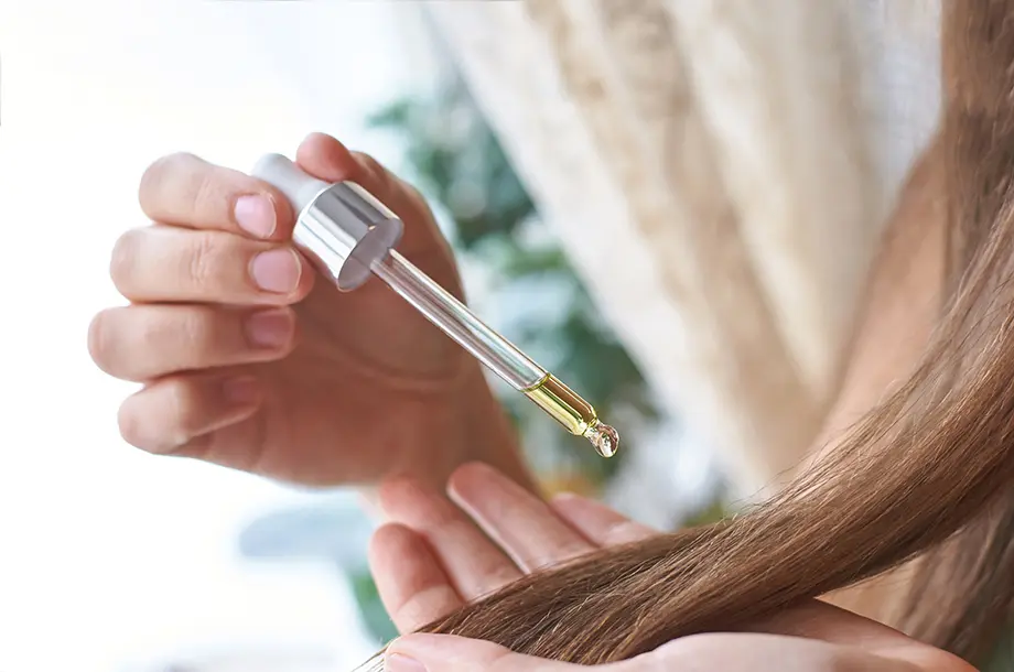 femme mettant des gouttes de soins sur ses cheveux